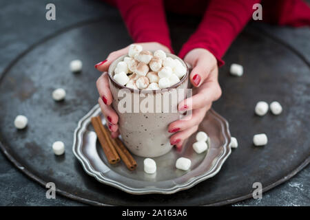 Donna di mani tazza di cioccolata calda con marshmellows Foto Stock