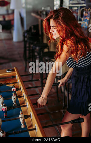 Giovane donna a giocare a biliardino in un bar sport Foto Stock