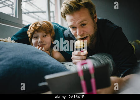 Padre e Figlio con lo smartphone e microfono a casa Foto Stock