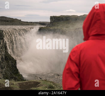 Giovane donna guardando le cascate di Dettifoss, Islanda Foto Stock