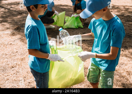Gruppo di volontariato bambini raccogliere rifiuti in un parco Foto Stock