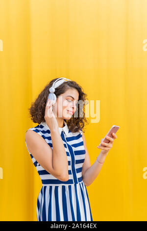 Ritratto di giovane donna con cuffie utilizza lo smartphone Foto Stock