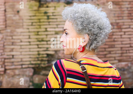 Profilo di trafitto donna matura con auricolari Foto Stock