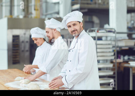 Baker con la pasta in mano in panetteria. Foto Stock