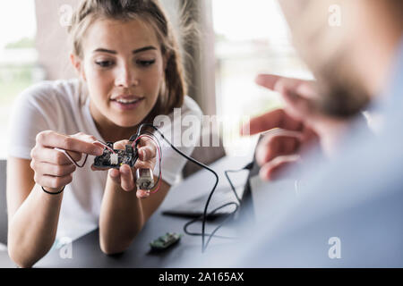 Giovane donna e uomo che lavora su apparecchiature per computer in ufficio Foto Stock