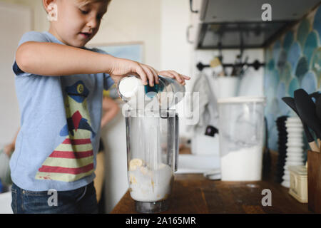 Ragazzo cucinare frittelle di banane in cucina a casa Foto Stock