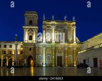 La facciata della cattedrale illuminata a Brindisi contro il cielo chiaro di notte Foto Stock