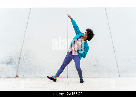 Giovane uomo parigamba dancing, muro bianco in background Foto Stock
