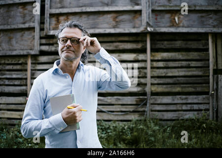 Ritratto di uomo maturo con i notebook, mano sui bicchieri Foto Stock