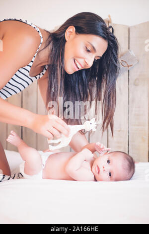 Felice madre giocando con il bambino giacente sul letto Foto Stock