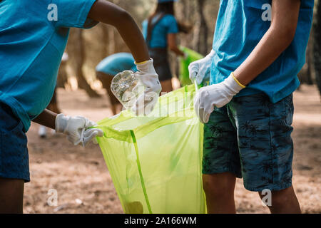 Close-up di volontariato bambini raccogliere rifiuti in un parco Foto Stock