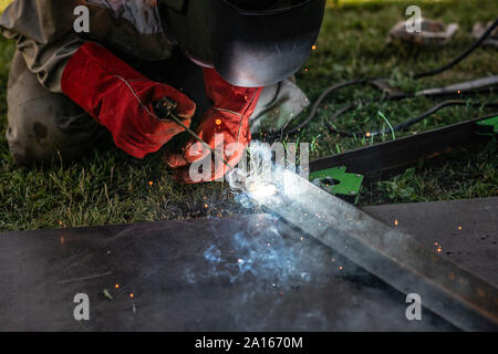 Uomo di metallo di saldatura nel suo cortile Foto Stock