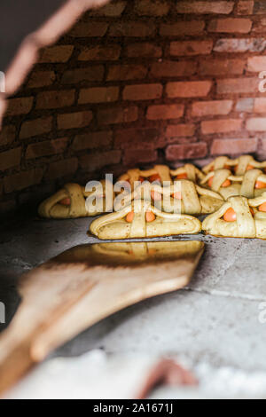 Close-up di pizza peel disponendo Mona de Pascua in stufa a legna Foto Stock