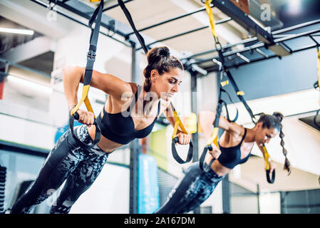 Gemelle facendo sospensione traning in palestra Foto Stock