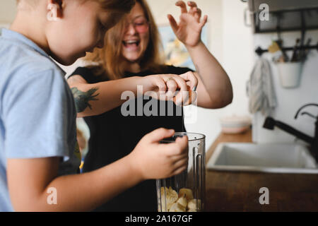 Madre e figlio cucinare frittelle di banane in cucina a casa Foto Stock