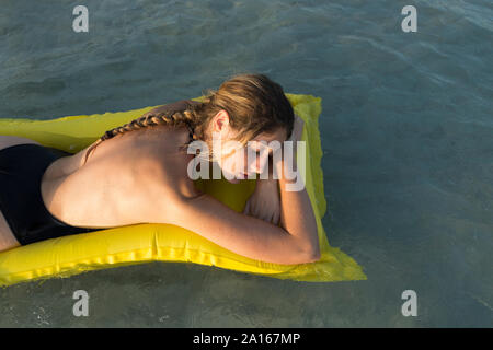 Giovane donna sdraiata su giallo airbed e dormire Foto Stock