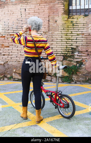 Vista posteriore della donna con la bicicletta smartphone portante nella sua tasca Foto Stock