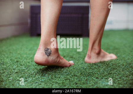 Close-up di una donna di tatuati passeggiate a piedi su erba artificiale Foto Stock