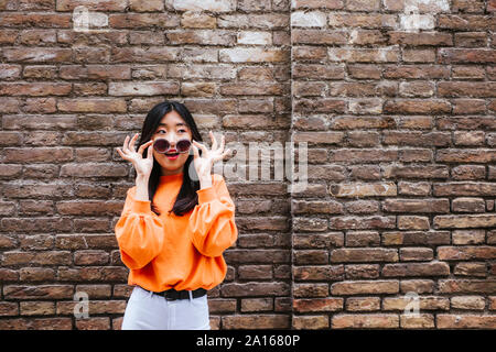 Donna asiatica con occhiali da sole guardando lateralmente Foto Stock
