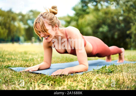 Athletic donna facendo esercizi tavoloni all'aperto nel parco Foto Stock