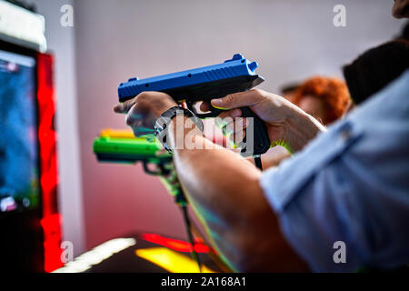 Close-up di amici a giocare e sparare con le pistole in una sala giochi Foto Stock