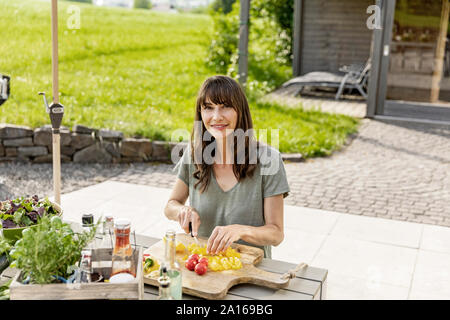 Ritratto di donna sorridente preparare un insalata sul tavolo da giardino Foto Stock