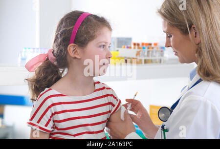 Medico donna dando una giovane ragazza di una vaccinazione di routine nella clinica Foto Stock