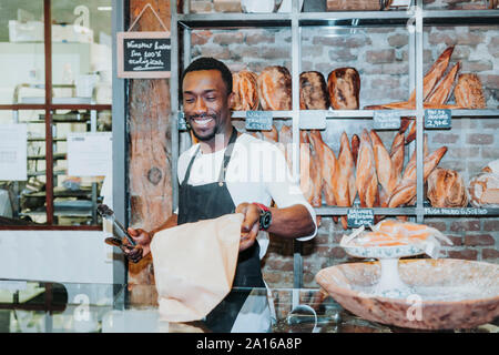 Uomo sorridente a lavorare in una panetteria Foto Stock