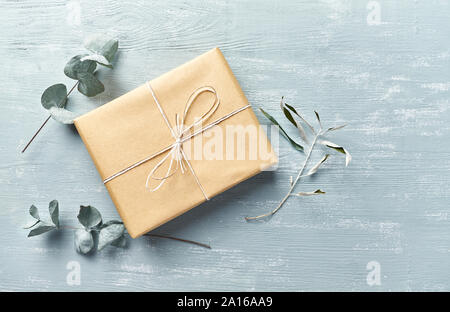 Confezione regalo e asciugare le foglie di eucalipto su vintage sfondo di legno. Lay piatto. Spazio di copia Foto Stock