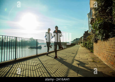 Due adolescenti fare jogging lungo il fiume Tamigi, London, Regno Unito Foto Stock