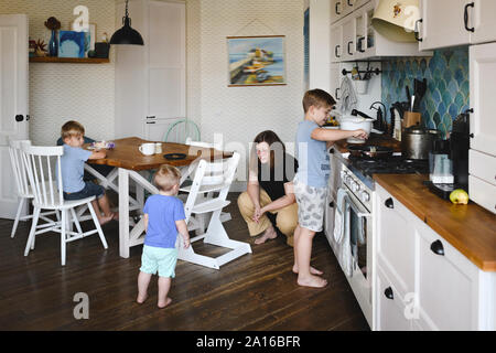 Madre con i suoi tre figli in cucina Foto Stock