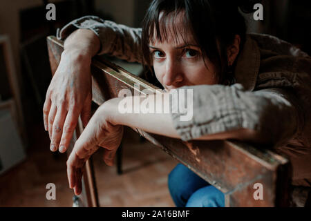 Ritratto di una donna pittore nel suo studio appoggiata sulla cornice immagine Foto Stock