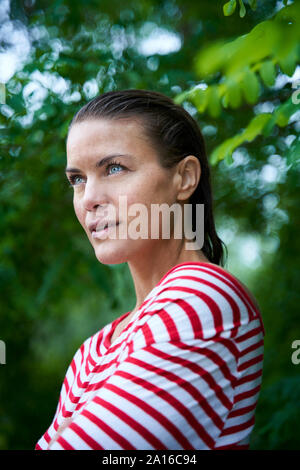 Ritratto di pensieroso donna con capelli bagnati indossando striped top in natura Foto Stock
