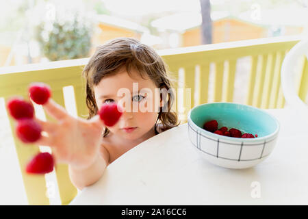 Carino bambina con lamponi a portata di mano Foto Stock