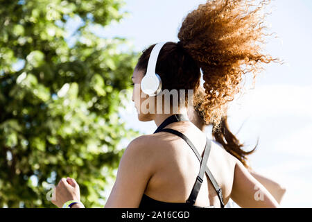 Sportivo da donna con cuffie in esecuzione Foto Stock