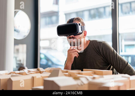 Uomo con modello architettonico in ufficio indossando occhiali VR Foto Stock