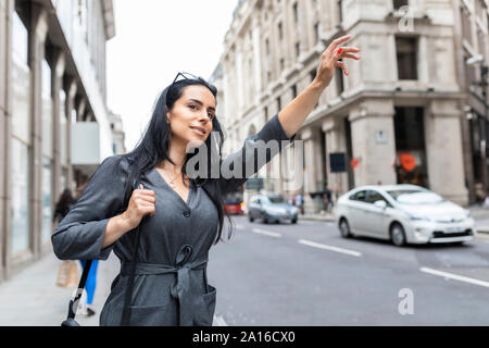 Donna della città salutando un taxi, London, Regno Unito Foto Stock