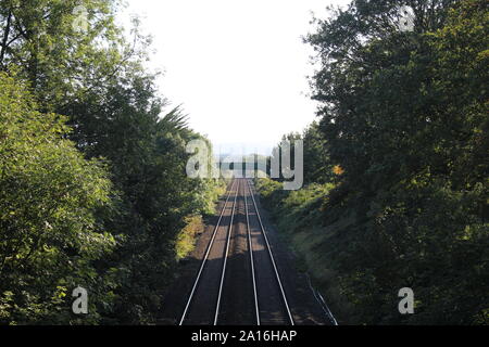 Immagine di una traccia ferroviaria presa da un ponte sopra la linea, che conduce le linee in distanza Foto Stock