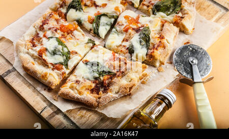 La Pizza Margherita con basilico su un tagliere. Close-up. Inquadratura orizzontale. Sfondo arancione Foto Stock