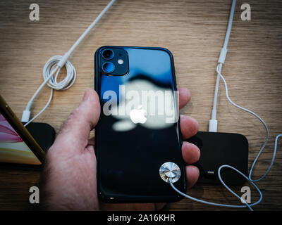 Parigi, Francia - Sep 20, 2019: vista dal di sopra della man mano che tiene il nero nuovo iPhone 11 in Apple Store come lo smartphone dal computer Apple va in vendita Foto Stock