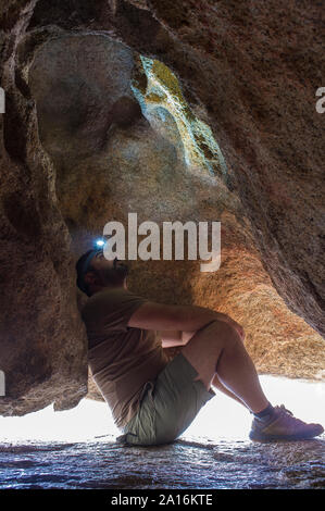 L'uomo osservando lo schema di epoca preistorica all'interno dipinti del masso di granito a monumento naturale di los Barruecos, Estremadura, Spagna Foto Stock