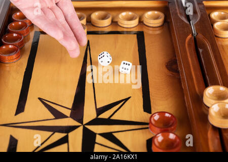 Una mano lancia dadi bianco su un bordo del backgammon. close up. Foto Stock