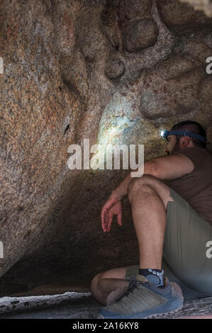 L'uomo osservando lo schema di epoca preistorica all'interno dipinti del masso di granito a monumento naturale di los Barruecos, Estremadura, Spagna Foto Stock