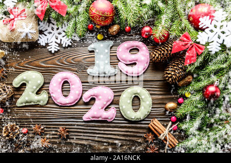 Colorata cucito cifre 2020 2019 di polkadot tessuto con decorazioni di Natale lay piatto su sfondo di legno Foto Stock