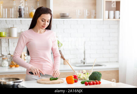 Giovane donna il taglio di verdure fresche in cucina Foto Stock