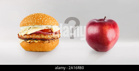 Burger e Apple su uno sfondo grigio con la questione tra Foto Stock