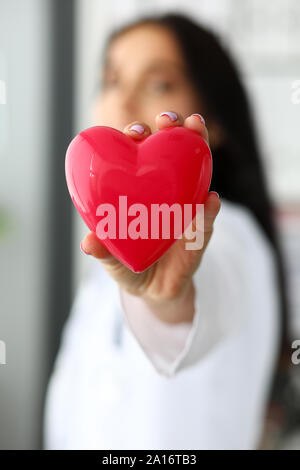 Cardiolog femmina tenendo in armi giocattolo rossa cuore Foto Stock