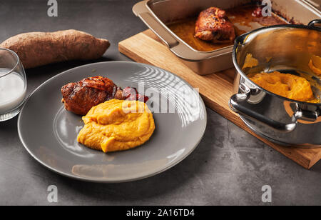 Serviti deliziosi purè di patate dolci con latte di cocco e pollo arrosto gamba. Immagine rappresenta una sana paleo mangiare, malattia autoimmune un trattamento Foto Stock