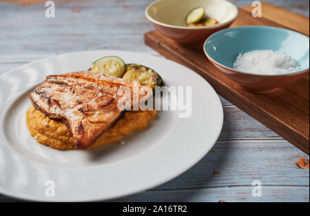 Purea di patate dolci con latte di cocco e il salmone grigliato sulla luminosa sullo sfondo del mediterraneo. Immagine rappresenta una sana paleo mangiare, malattia autoimmune Foto Stock