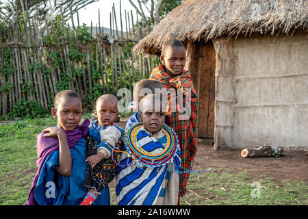 Masai bambini in abito tradizionale sono responsabili per i fratelli più giovani nel villaggio. Foto Stock